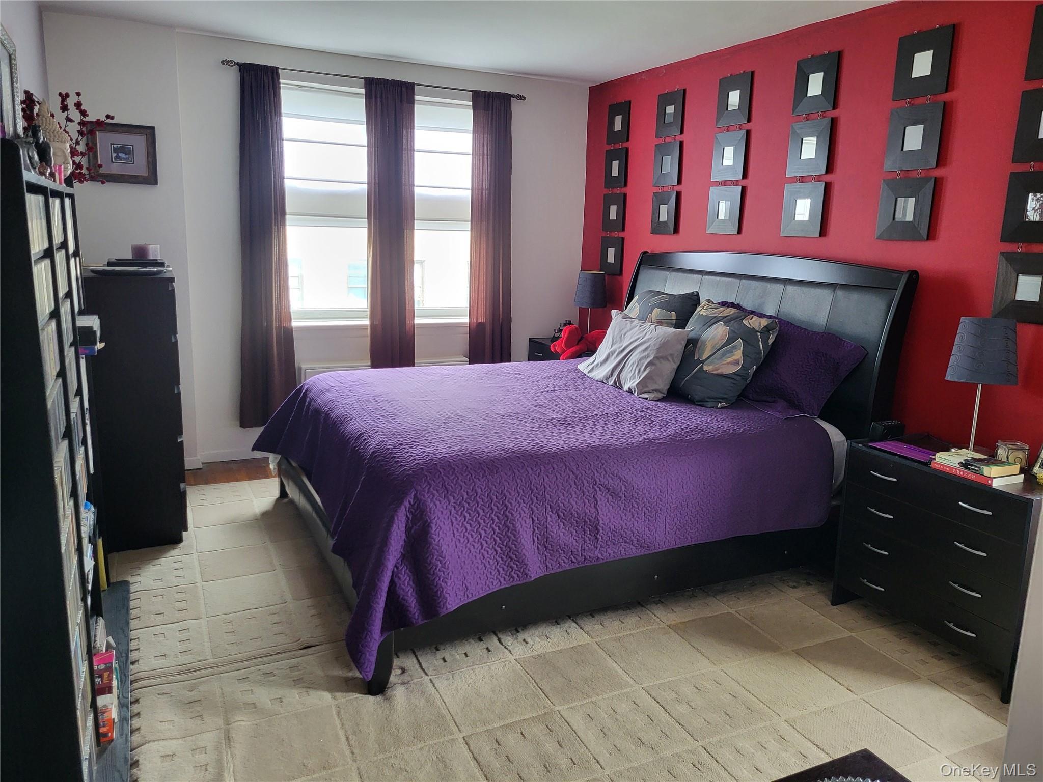 3176 Decatur Avenue, Unit 6H Bronx, NY 10467 - Photo 4 of 12 Bedroom featuring a deep red accent wall, a wide window with blinds, and a patterned area rug