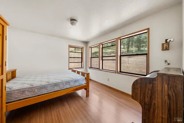 a spacious bedroom with a bed and wooden floor