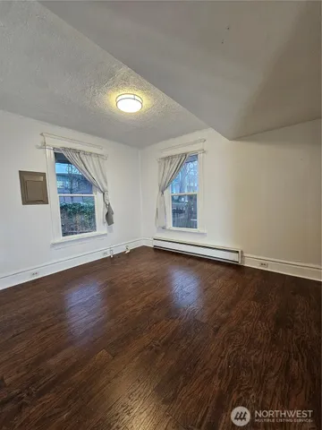 an empty room with wooden floor and windows