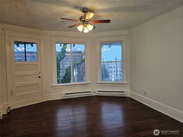 an empty room with wooden floor and windows