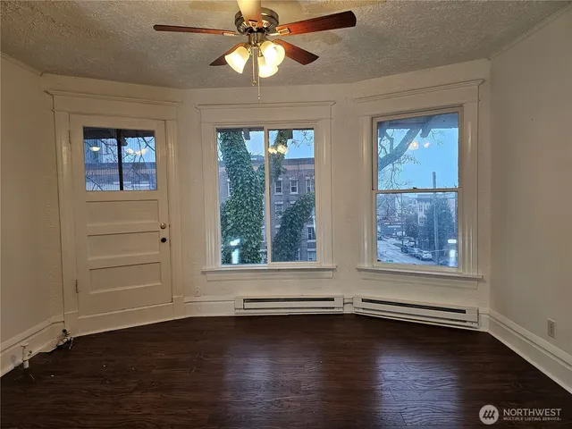 a view of an empty room with wooden floor and a window