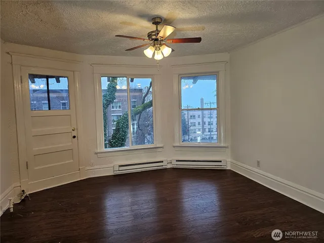 a view of an empty room with wooden floor and a window