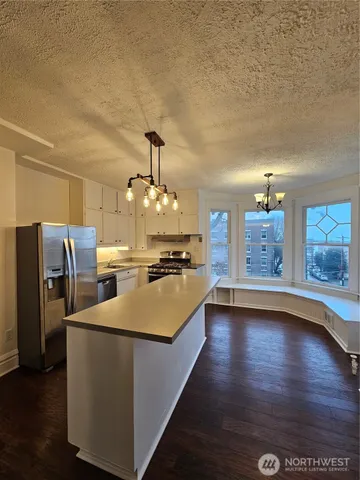 a large kitchen with a stove a refrigerator a sink dishwasher with wooden floor and cabinets