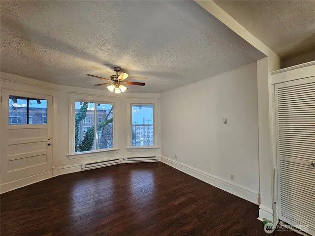 an empty room with wooden floor chandelier fan and windows