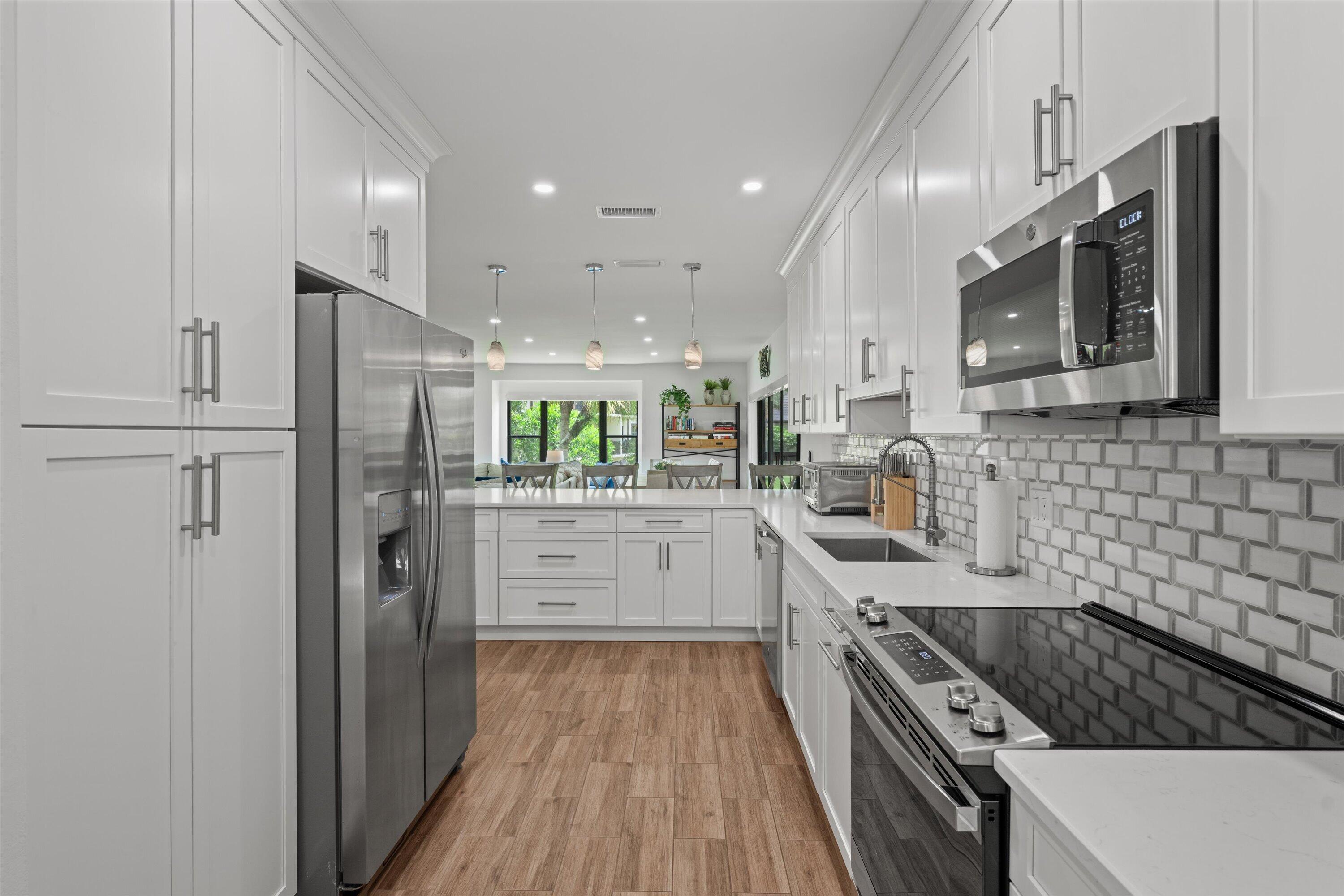 13400 Polo Road West, Unit 203 Wellington, FL 33414 - Photo 13 of 26 a kitchen with stainless steel appliances kitchen island granite countertop a refrigerator stove and sink
