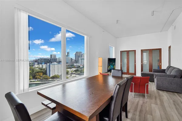 a living room with furniture floor to ceiling window wooden floor and a large window