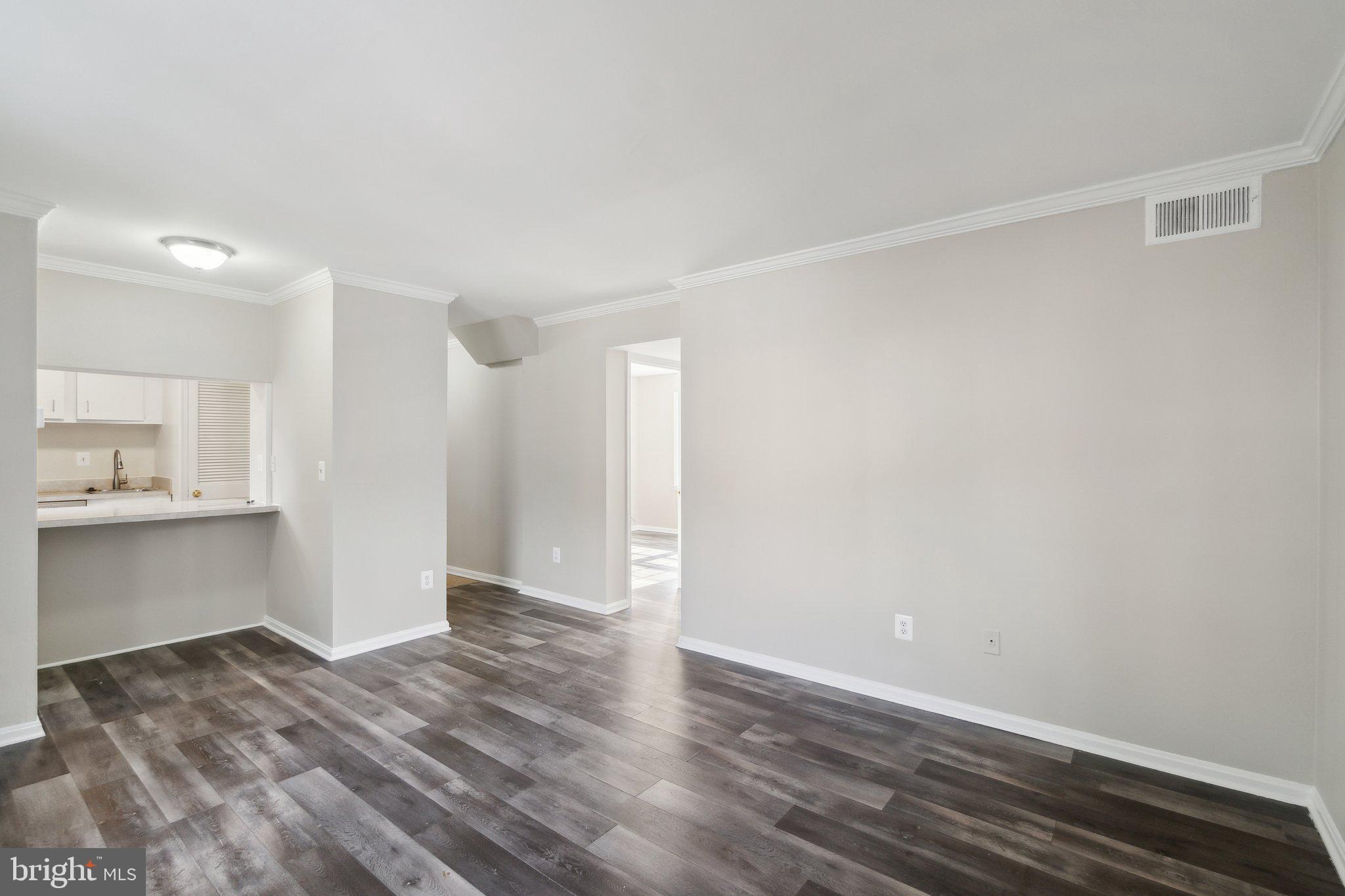 2016 37th Street Southeast, Unit 201 Washington, DC 20020 - Photo 8 of 17 a view of an empty room with wooden floor and kitchen