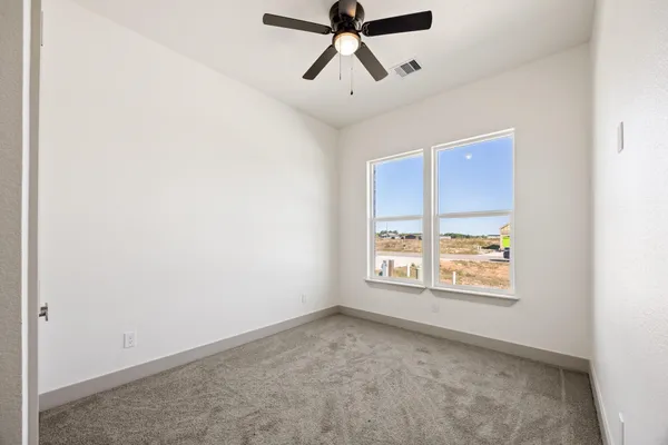 an empty room with windows and ceiling fan
