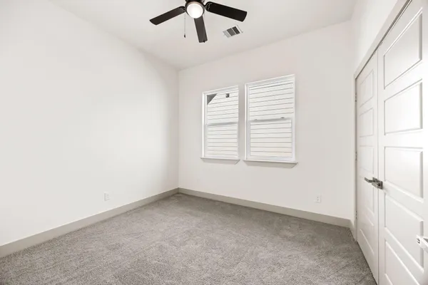 an empty room with a window and a ceiling fan