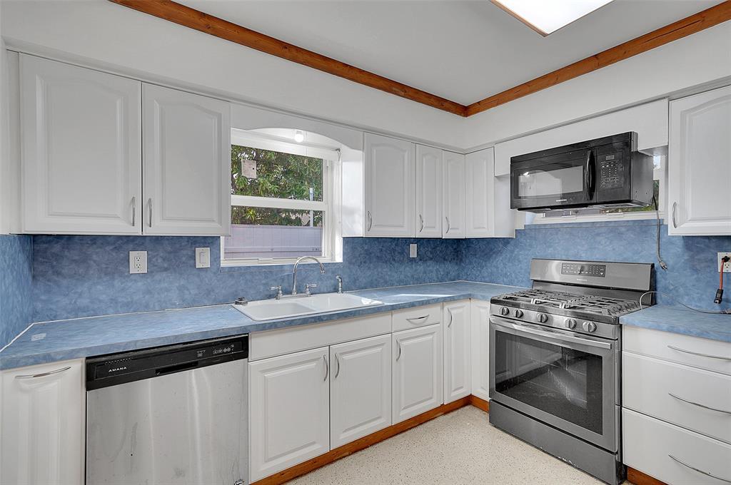 29 Southeast 8th Street Dania Beach, FL 33004 - Photo 16 of 42 a kitchen with white cabinets stainless steel appliances and sink
