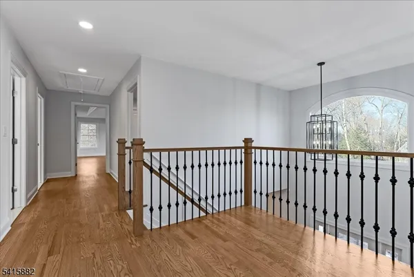 a view of a hallway with wooden floor and chandelier