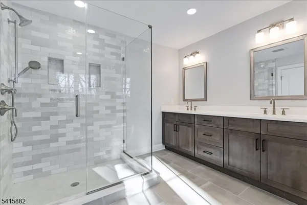 a bathroom with a double vanity sink mirror and shower
