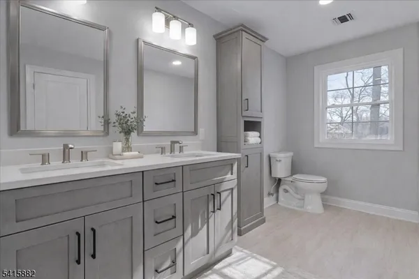 a bathroom with double vanity sink a toilet and a window