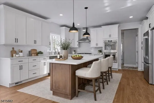 a kitchen with stainless steel appliances kitchen island granite countertop a sink a stove a refrigerator and island with wooden floor