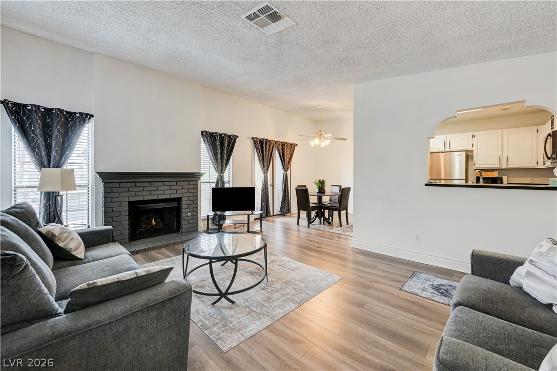 1751 East Reno Avenue, Unit 228 Las Vegas, NV 89119 - Photo 3 of 39 A well-lit living area showcases a cozy fireplace and seamless flow into the dining space.