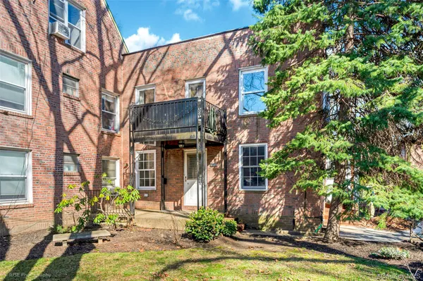 a view of a building with a small yard plants and large tree