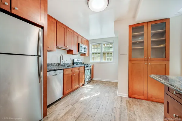 a kitchen with granite countertop stainless steel appliances a refrigerator a sink and cabinets