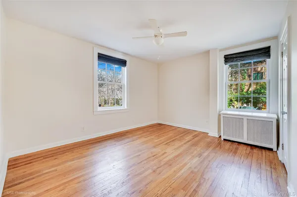 a view of an empty room with a window and wooden floor