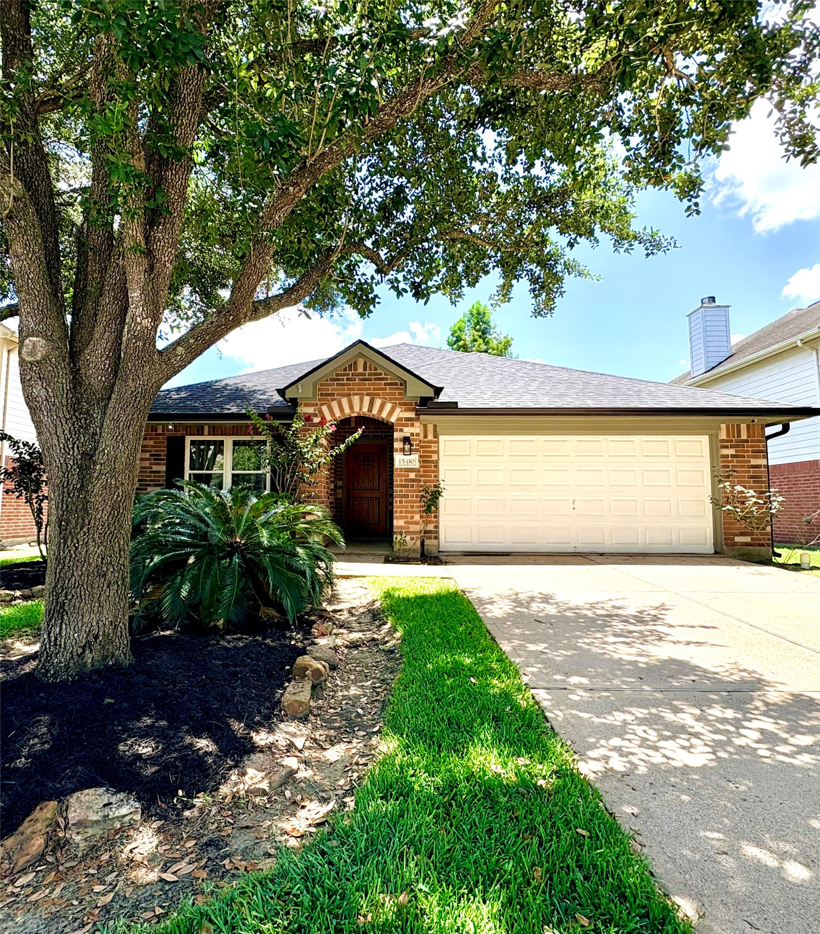 15410 Redbud Berry Way Cypress, TX 77433 - Photo 1 of 49 Charming brick home with a welcoming archway entrance, two-car garage, and a well-maintained front yard featuring mature trees and lush greenery.