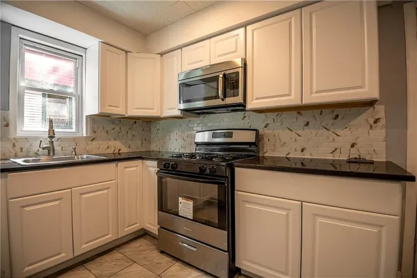 a kitchen with stainless steel appliances granite countertop white cabinets granite counter tops and a wooden floors