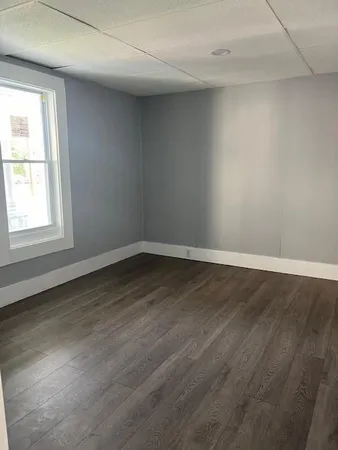 an empty room with wooden floor and window