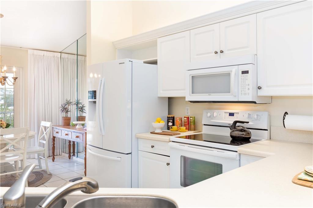 835 Tanbark Drive, Unit 203 Naples, FL 34108 - Photo 4 of 17 a kitchen with white cabinets and white appliances
