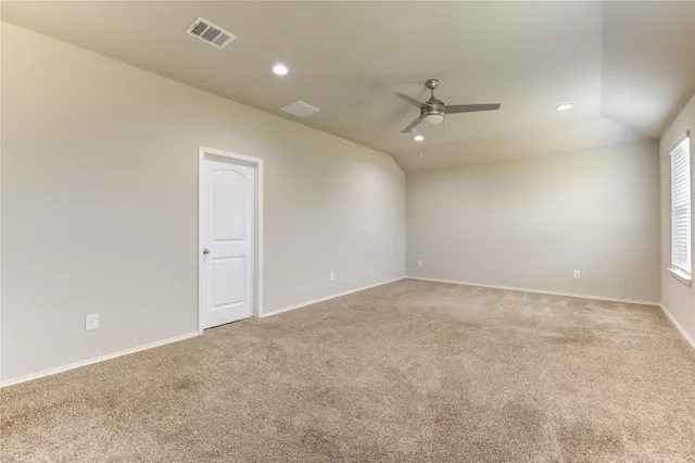 an empty room with ceiling fan and window