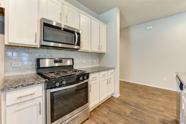 a kitchen with stainless steel appliances granite countertop a stove microwave and sink