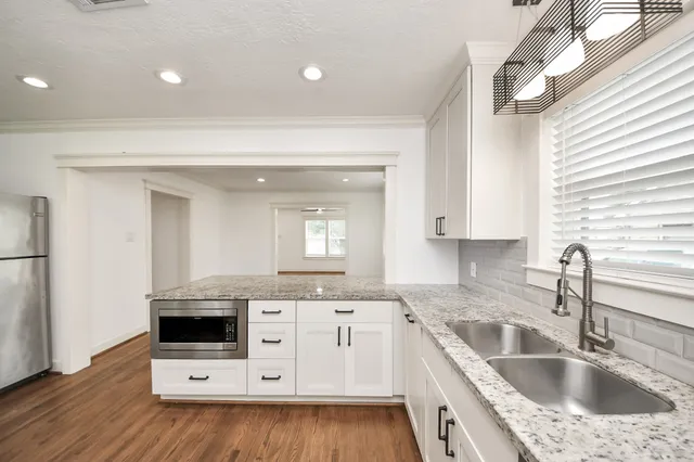 a view of a kitchen counter space a sink wooden floor and appliances