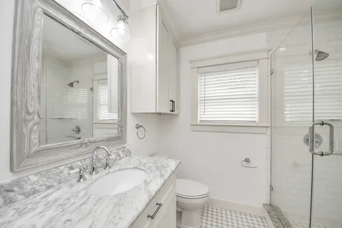 a bathroom with a granite countertop sink a toilet and a mirror