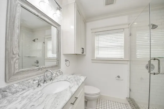 a bathroom with a granite countertop sink a toilet and a mirror