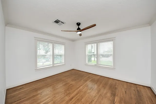 a view of empty room with wooden floor and fan
