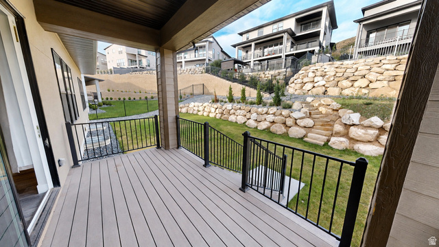 5502 North Valley View Road Lehi, UT 84048 - Photo 30 of 33 Covered deck featuring wood-finish flooring, black metal railings, and a multi-level rock retaining wall in the backyard
