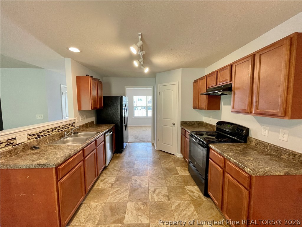 92 Hallow Oak Street Spring Lake, NC 28390 - Photo 5 of 11 a large kitchen with stainless steel appliances granite countertop a stove top oven a sink dishwasher and wooden cabinets with wooden floor