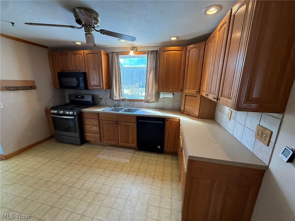 6784 Old Zoarville Road Northeast Dover, OH 44622 - Photo 11 of 50 Kitchen with black appliances, tasteful backsplash, light countertops, a ceiling fan, and wood finish cabinetry