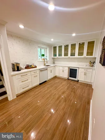 a large kitchen with granite countertop a stove top oven a sink dishwasher and white cabinets with wooden floor