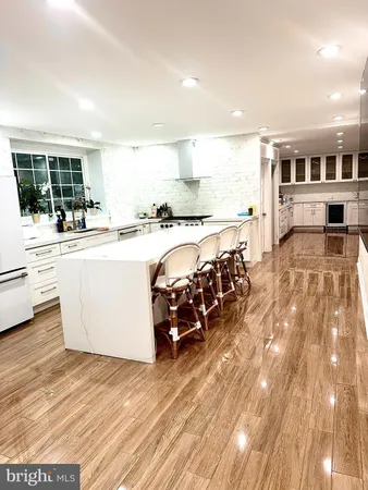 a large white kitchen with wooden floors and wide window