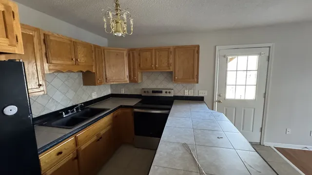 a kitchen with granite countertop stainless steel appliances a sink stove top oven and cabinets
