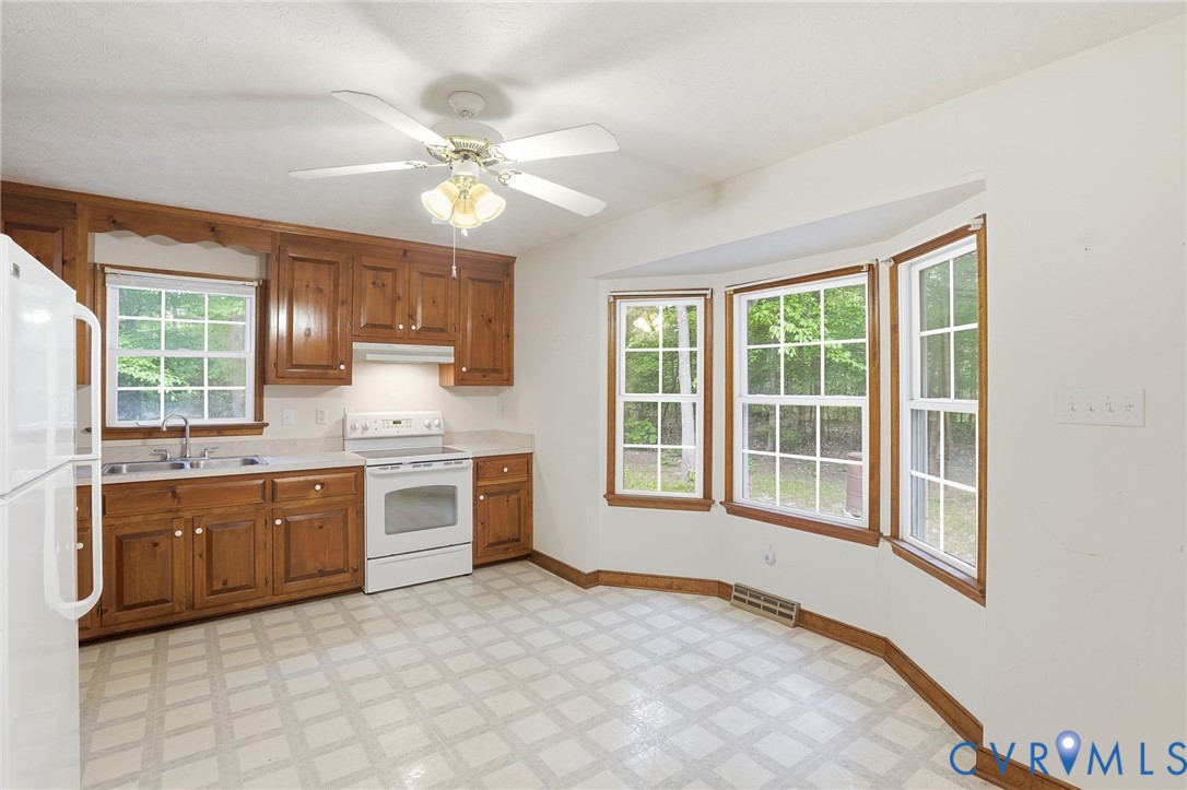 1917 Mahixon Road Manquin, VA 23106 - Photo 19 of 43 a large white kitchen with cabinets a sink a window and stainless steel appliances
