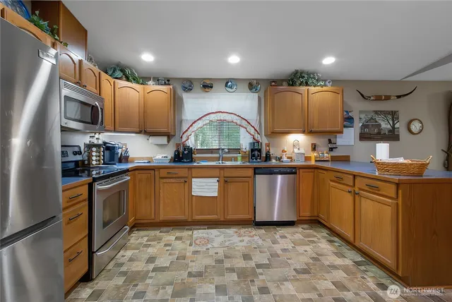 a kitchen with stainless steel appliances granite countertop a sink a stove top oven a chimney and cabinets
