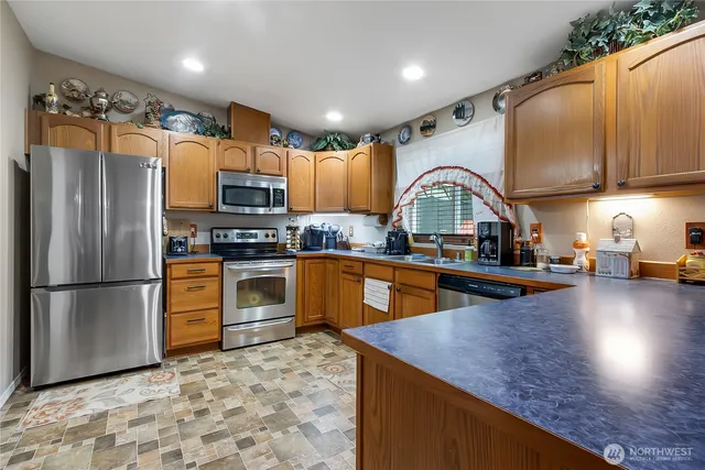 a kitchen with stainless steel appliances granite countertop a refrigerator a stove a sink dishwasher and a refrigerator with wooden floor