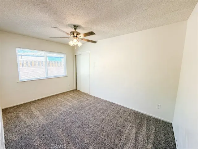 an empty room with windows and fan