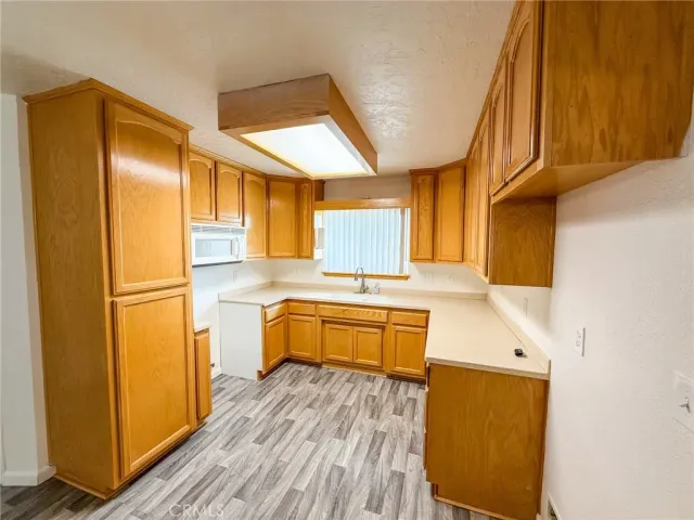 a kitchen with stainless steel appliances granite countertop a refrigerator a sink dishwasher and wooden cabinets with wooden floor