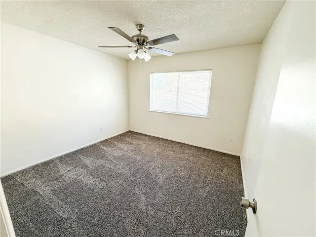 an empty room with a window and a fan
