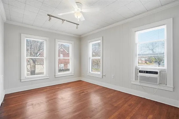 a view of empty room with wooden floor and fan