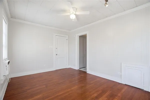 an empty room with wooden floor and fan