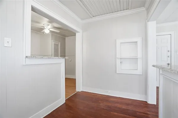 a view of a hallway with wooden floor and a bathroom