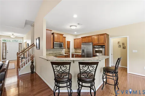 a kitchen with stainless steel appliances granite countertop a dining table chairs and granite counter tops