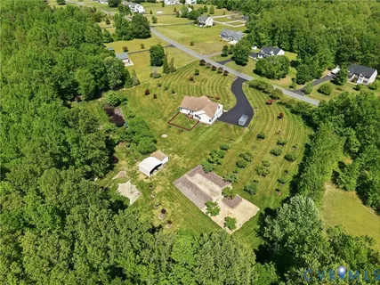 an aerial view of residential house with outdoor space and trees all around