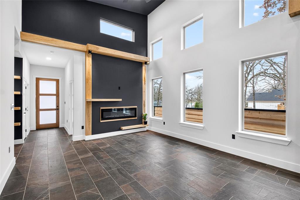 124 Aztec Drive Mabank, TX 75156 - Photo 15 of 33 Unfurnished living room featuring a high ceiling and a glass covered fireplace